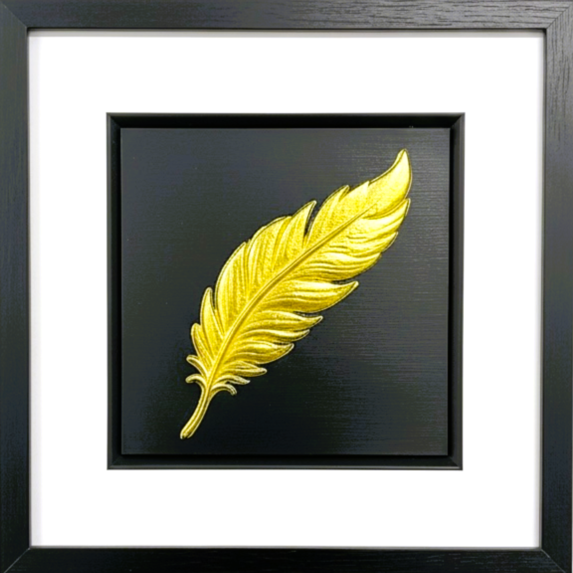 Handcrafted framed gold leaf wall art featuring a symbolic feather, displayed on a black background with white mount and black frame.
