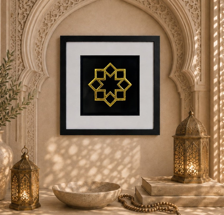 Framed Islamic 8 point star wall art with gold leaf design on a black background, styled in a warm neutral Islamic inspired alcove with lanterns and geometric shadows.