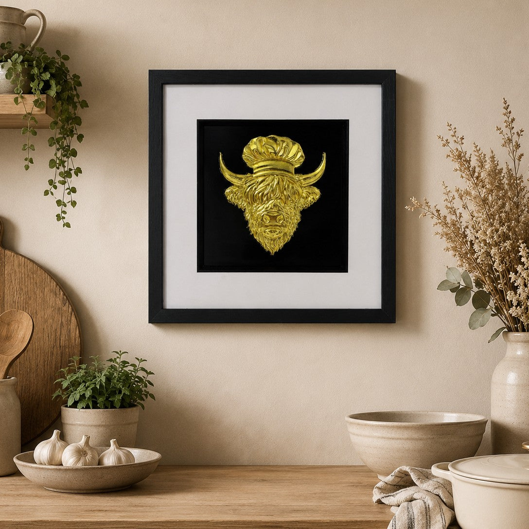 Framed Highland cow chef wall art with gold leaf design on a black background, styled in a warm neutral kitchen with rustic wood, ceramic bowls and premium country decor.