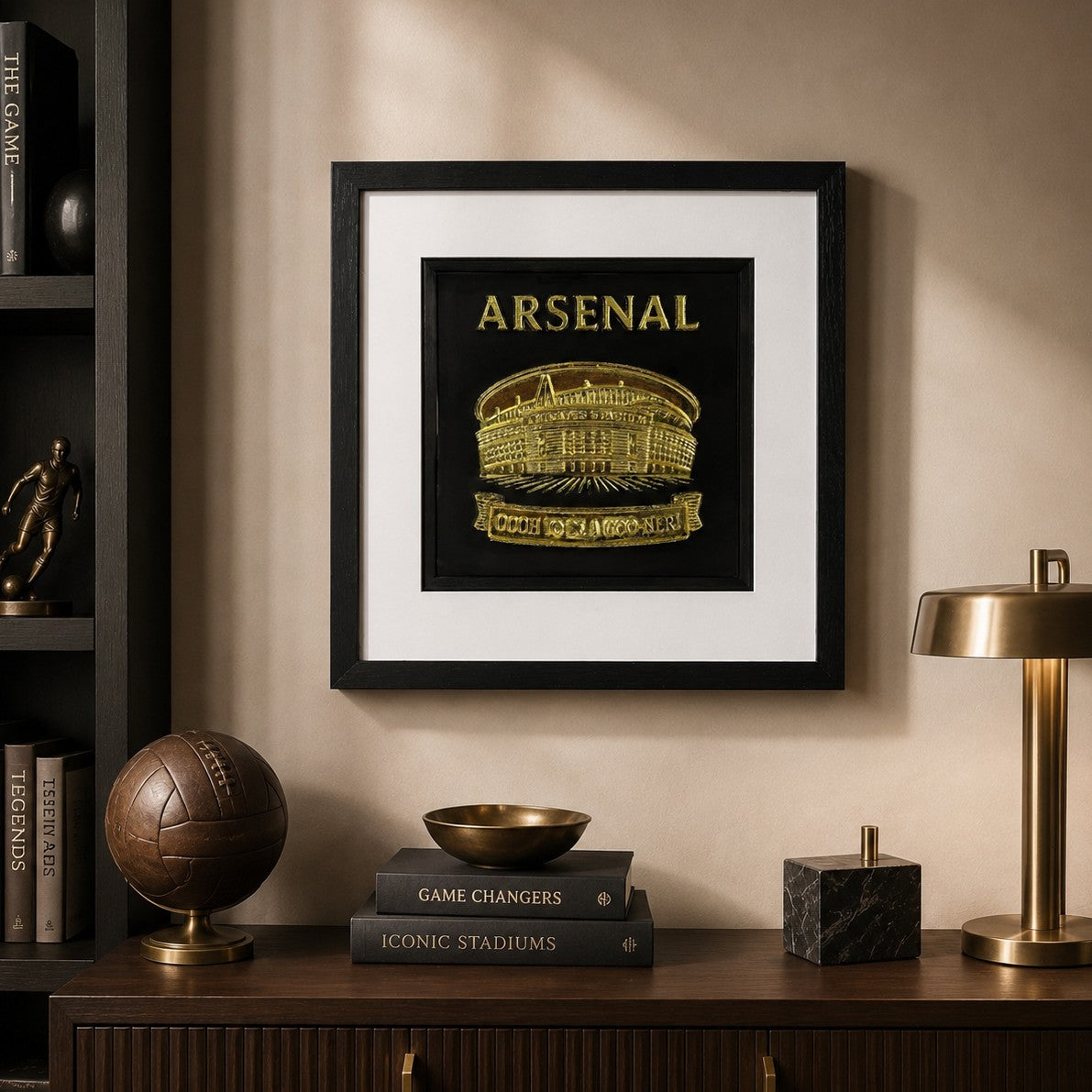 Framed gold Arsenal football stadium 3D wall art with black background and white mount, styled in a warm modern sports-inspired home office interior.