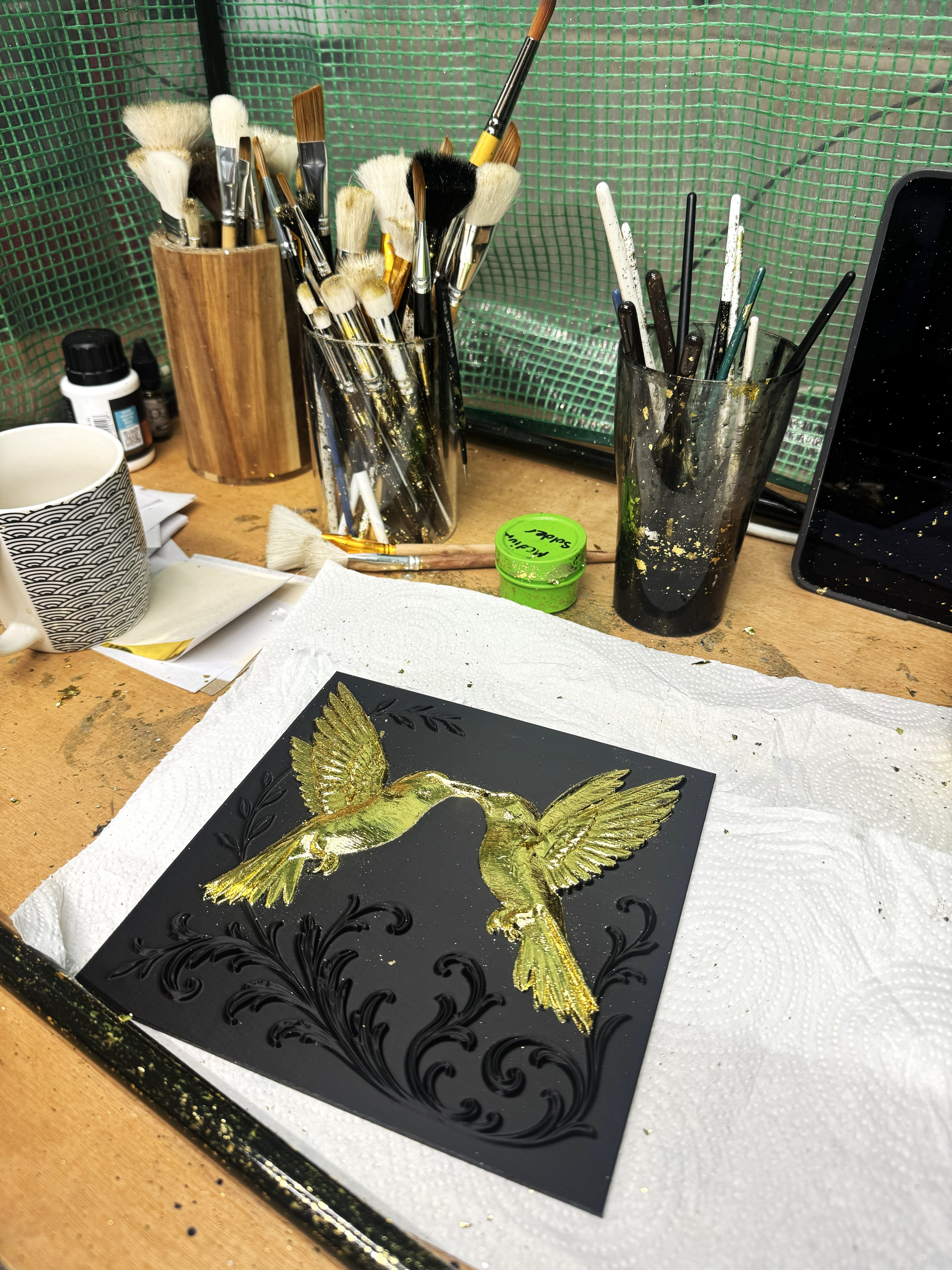 Gold leaf gilding tools and brushes with 3D hummingbird relief art in progress