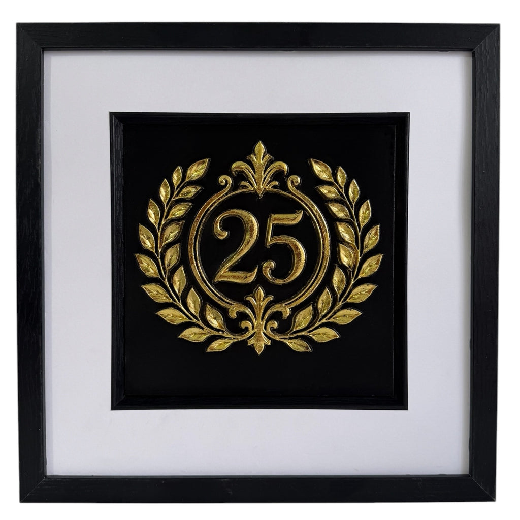 Straight-on Gold 25th anniversary laurel wreath framed artwork with raised number 25, black background, white mount, and black frame.