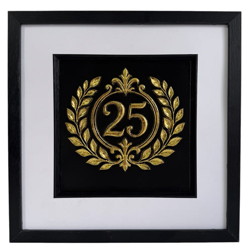 Straight-on Gold 25th anniversary laurel wreath framed artwork with raised number 25, black background, white mount, and black frame.