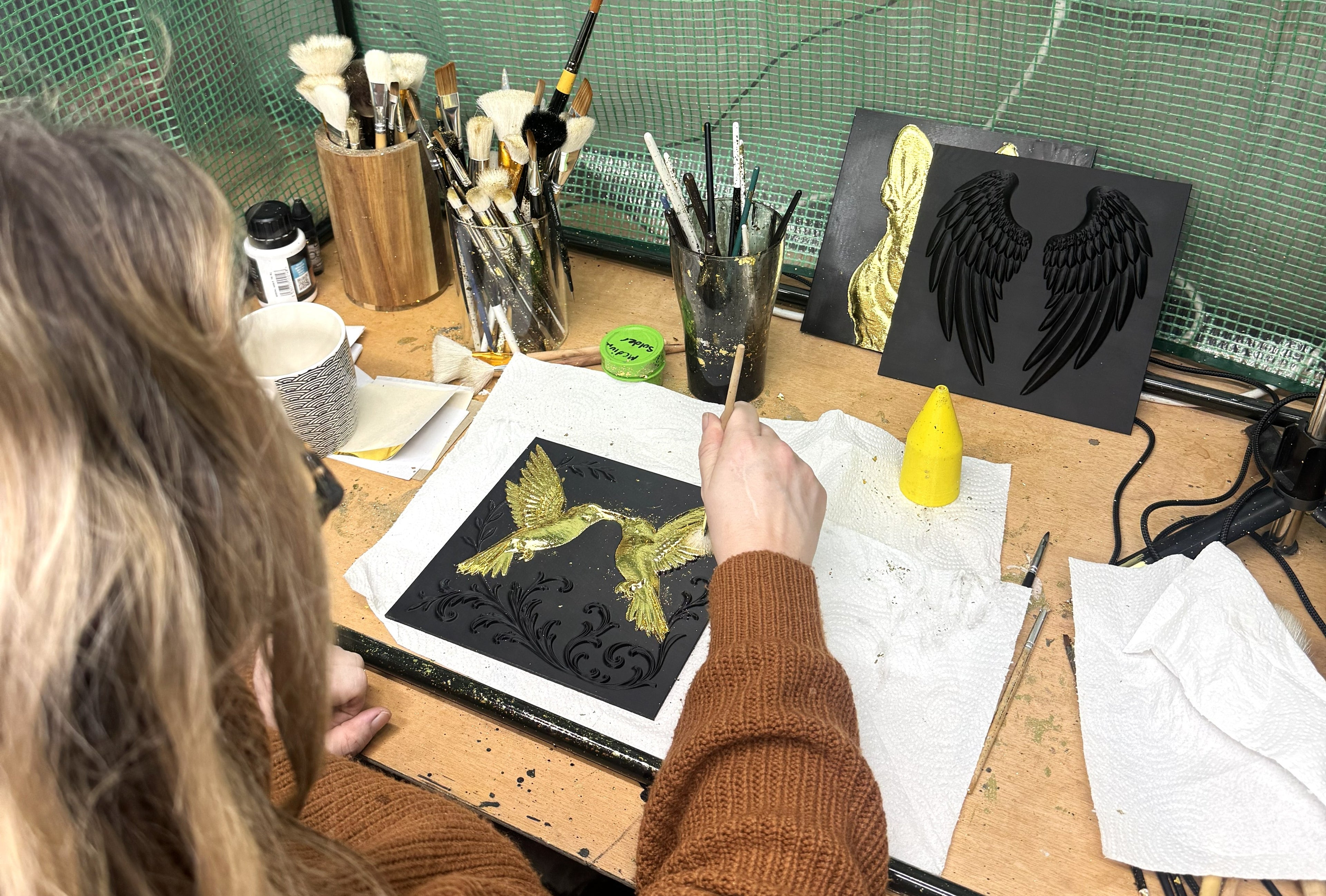 Artist Paula hand-gilding 3D hummingbird relief in UK studio