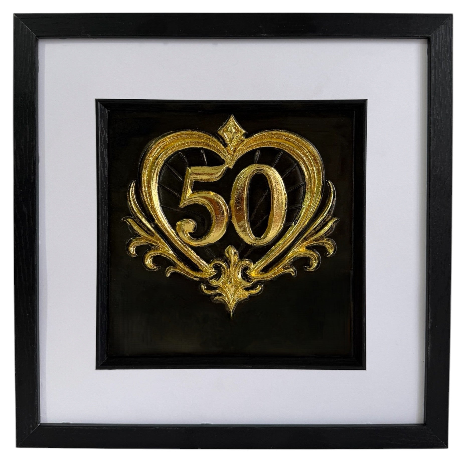 Straight-on Gold 50th anniversary heart framed artwork with raised number 50, ornate heart detail, black background, white mount, and black frame.