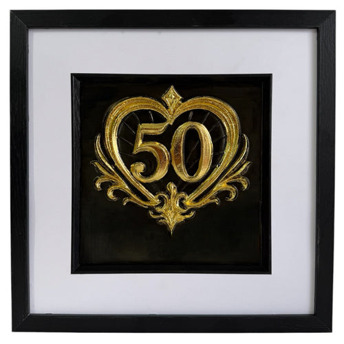Straight-on Gold 50th anniversary heart framed artwork with raised number 50, ornate heart detail, black background, white mount, and black frame.