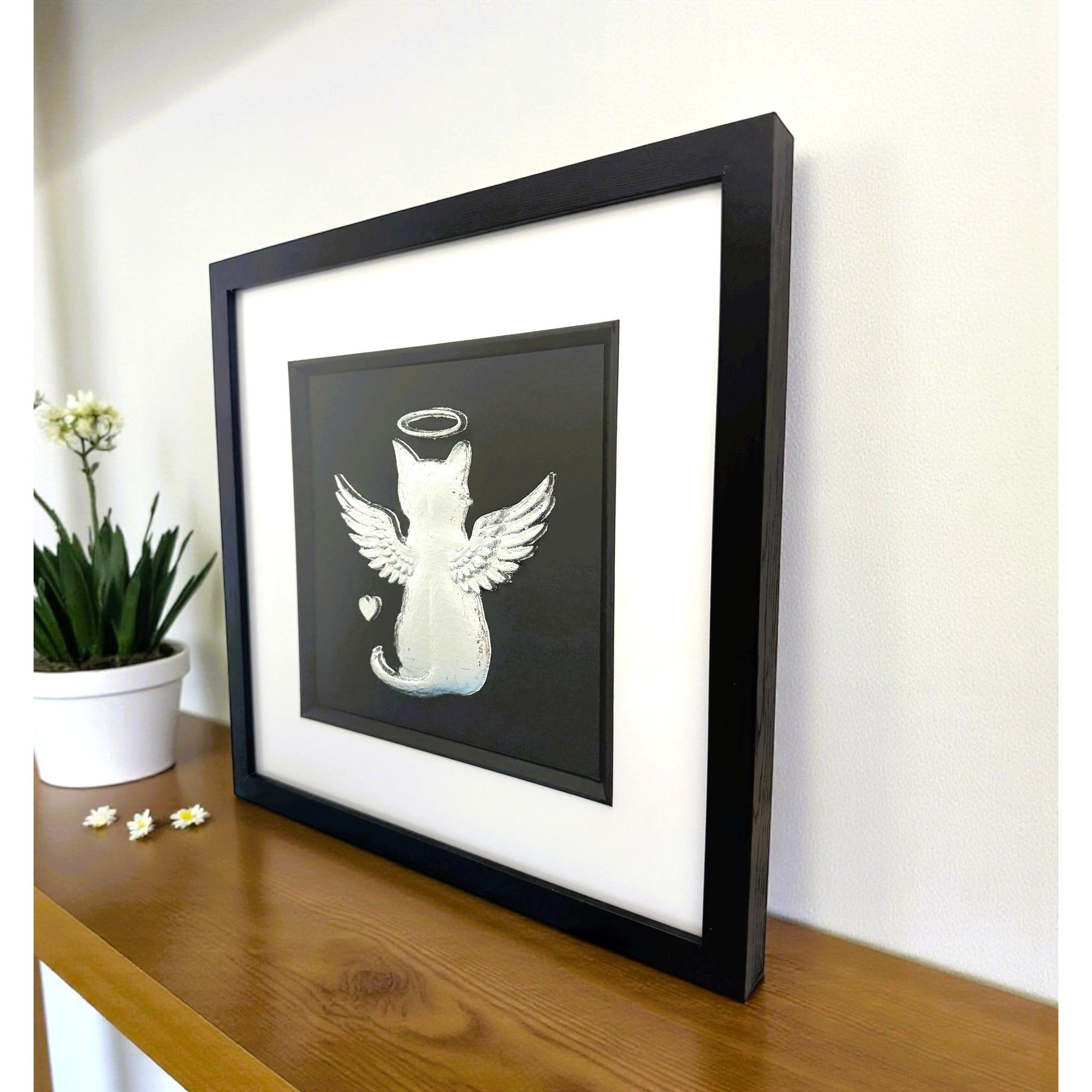 Angled desk view of silver leaf cat angel memorial wall art on a wooden surface