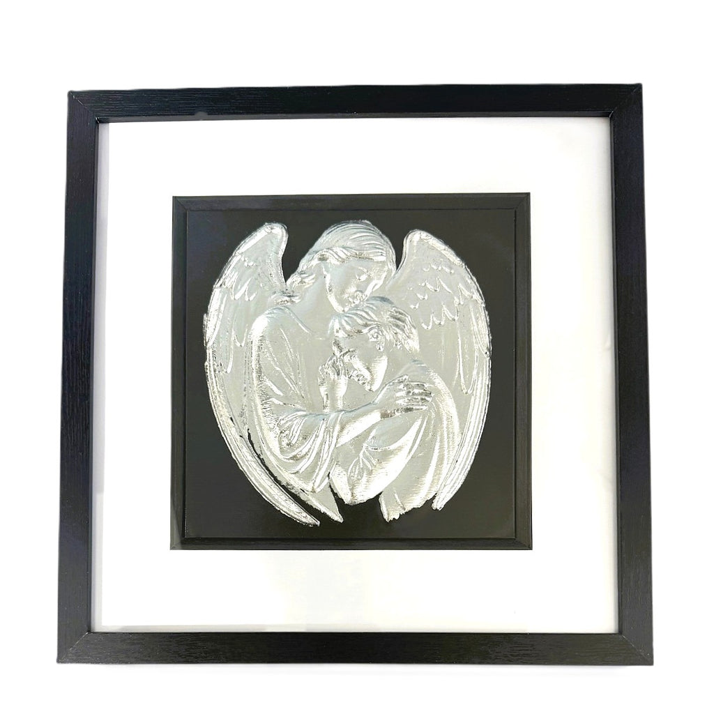 Silver leaf angel embracing a human figure framed in black wood with white mount on a black background