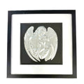 Silver leaf angel embracing a human figure framed in black wood with white mount on a black background