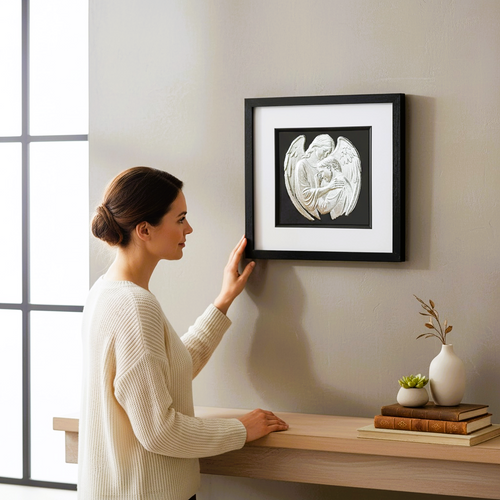 Lifestyle image showing angel embrace framed wall art displayed above a wooden console, viewed by a person for scale