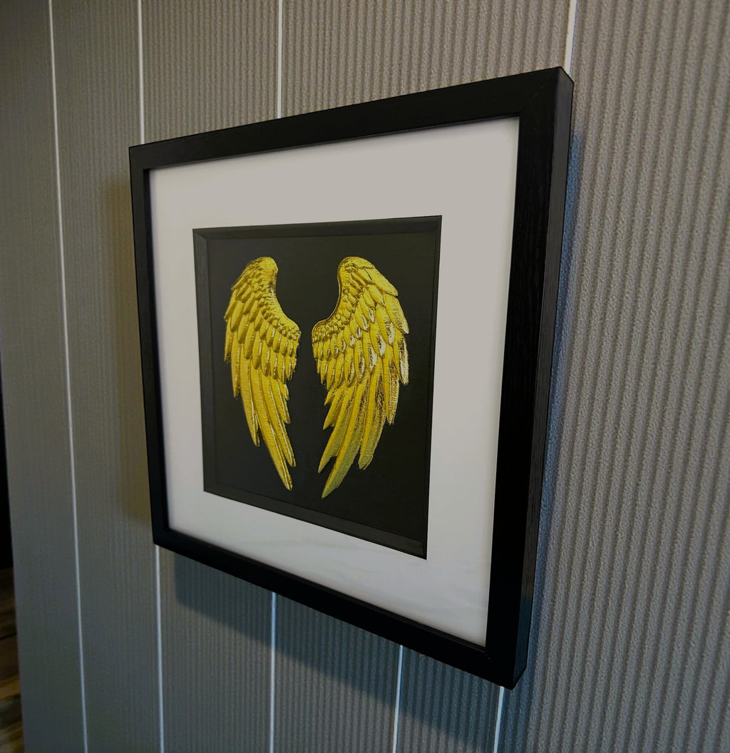 gold angel wing wall art mounted on a grey wall