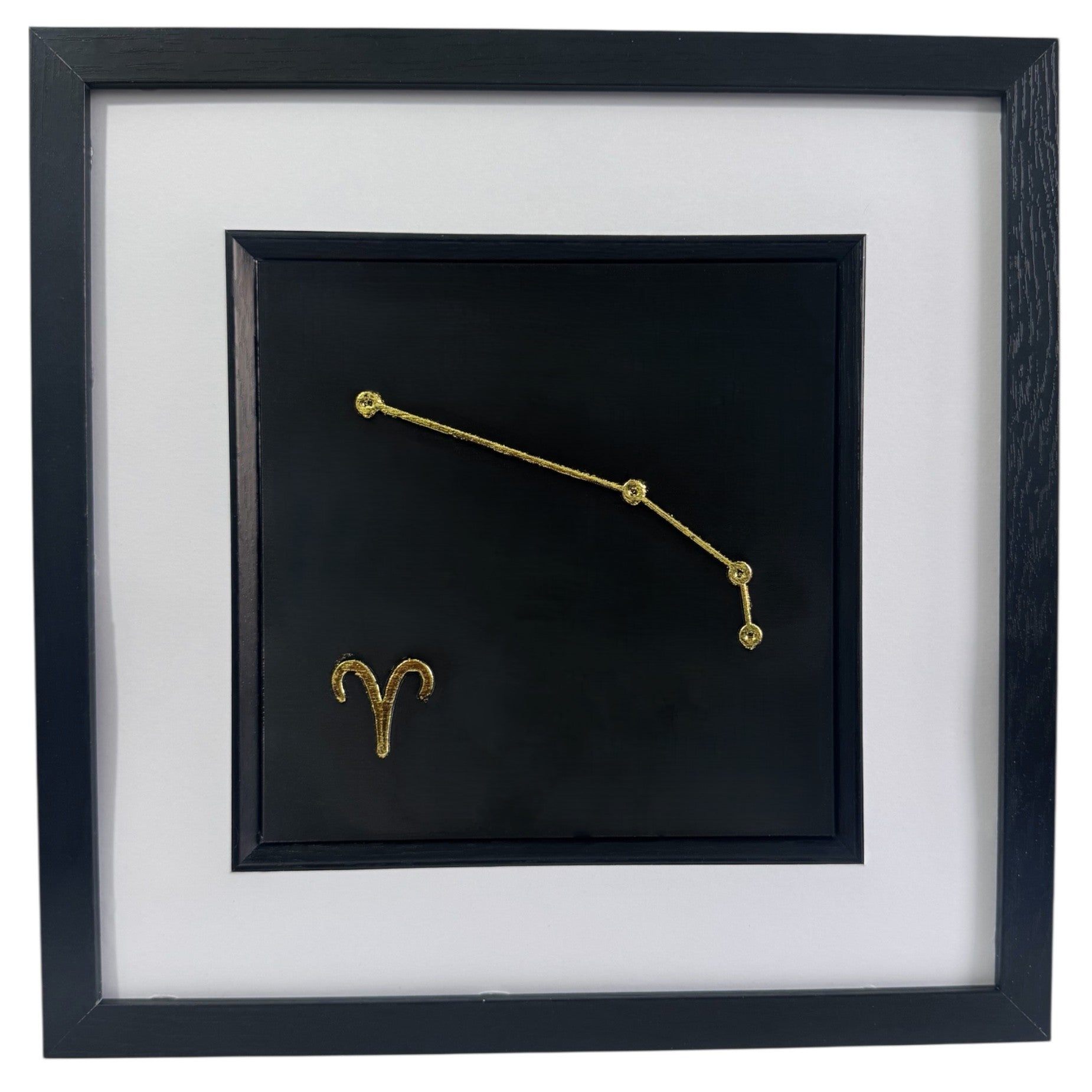 Framed Aries constellation wall art in gold leaf with star pattern and zodiac symbol, centred on a black background with white mount and black frame