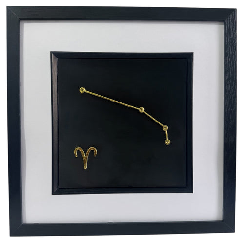 Framed Aries constellation wall art in gold leaf with star pattern and zodiac symbol, centred on a black background with white mount and black frame