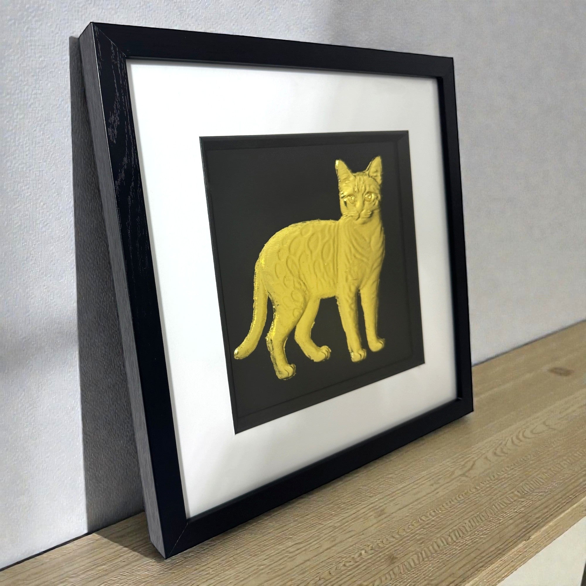 Bengal cat gold leaf framed wall art resting on a desk showing the frame profile and mount