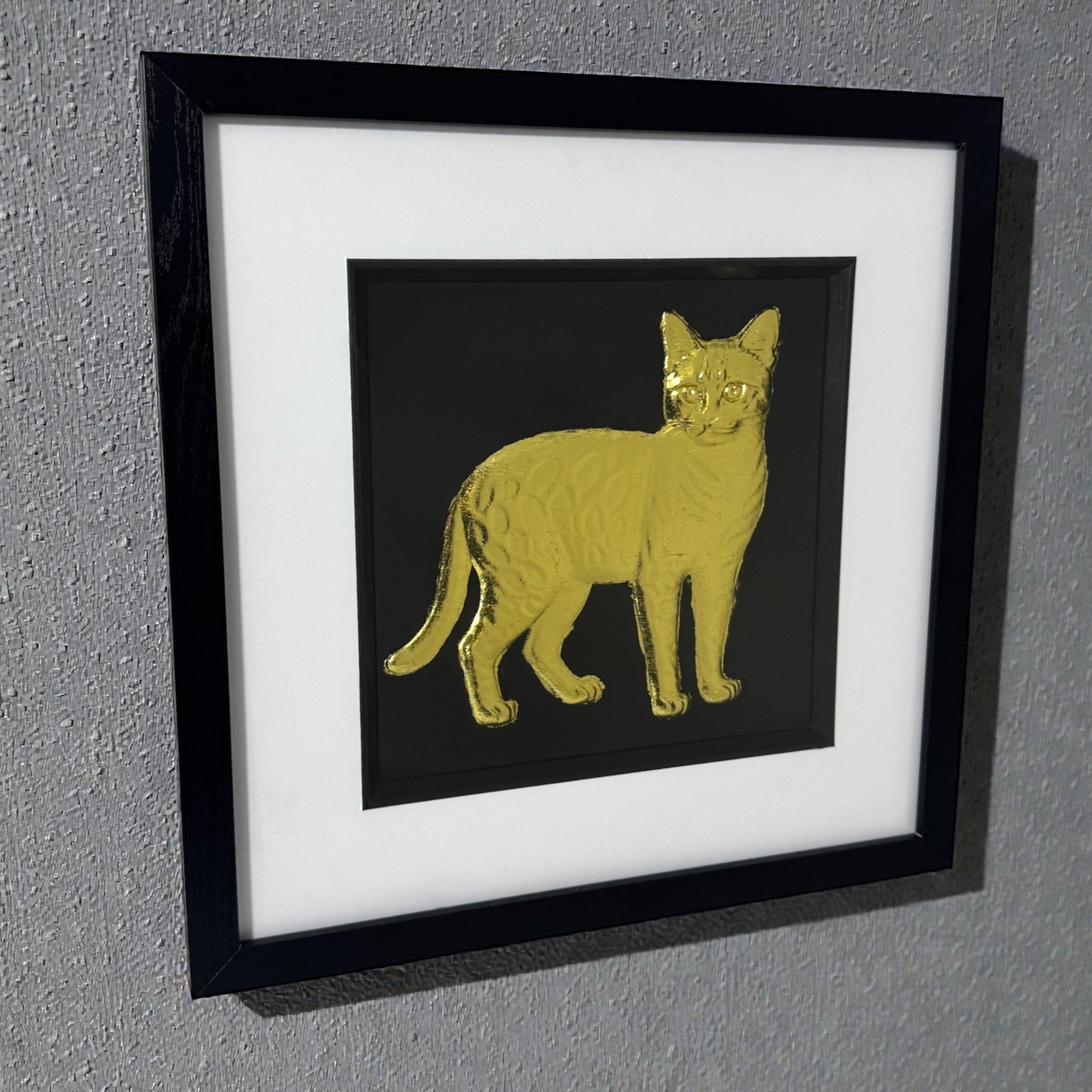Bengal cat gold leaf framed wall art hanging on a wall with black frame and white mount