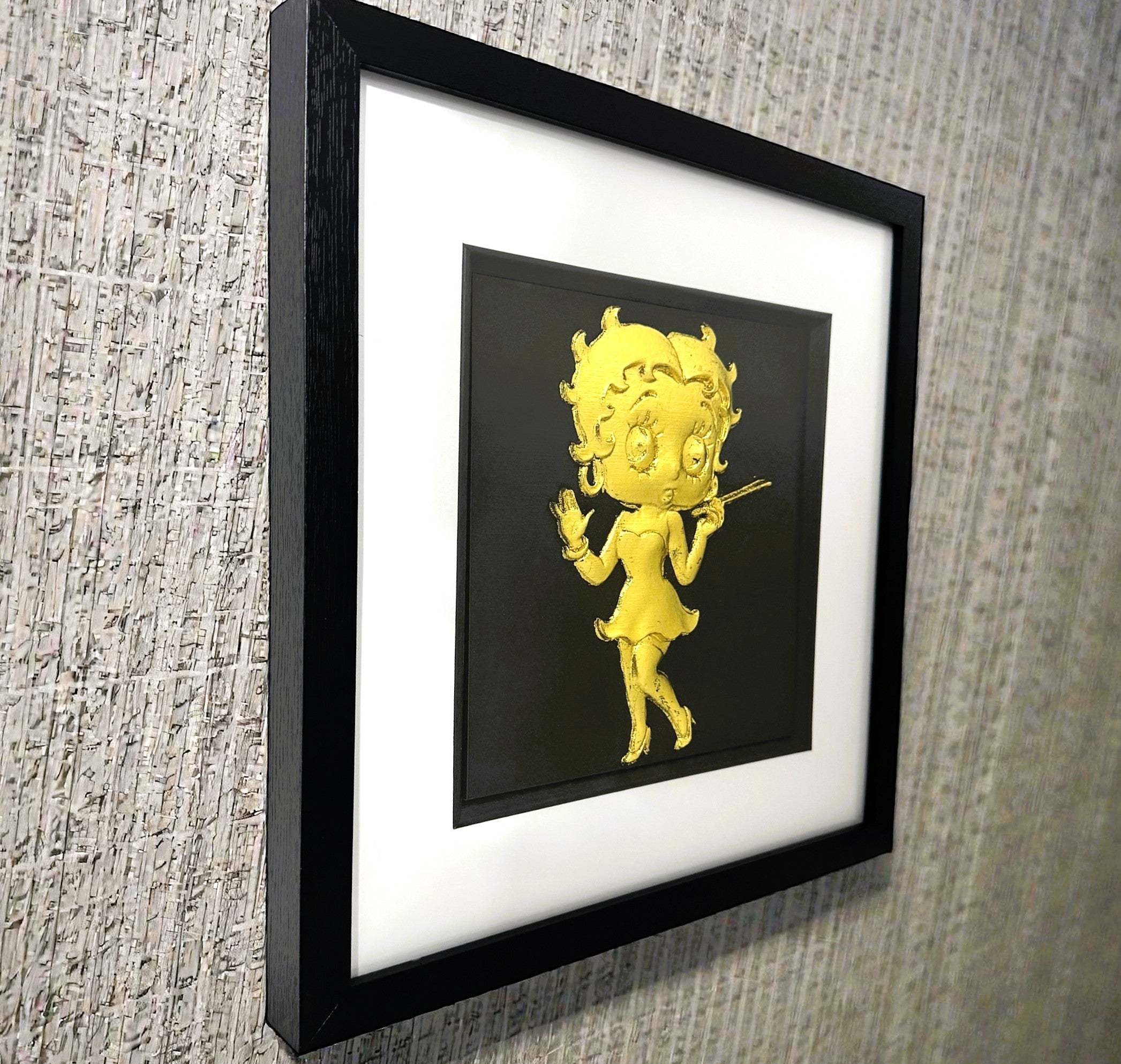 Angled view of gold leaf vintage cartoon icon framed wall art on wall