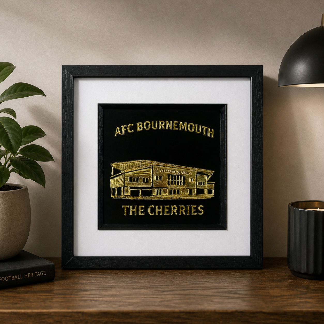 Lifestyle photo of gold AFC Bournemouth Vitality Stadium wall art displayed on a shelf with plant, lamp and candle.