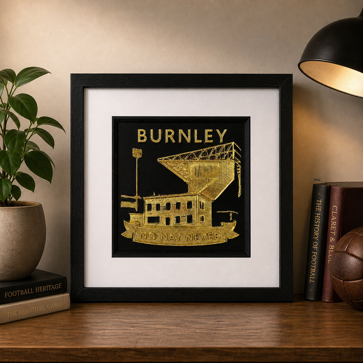 Lifestyle photo of Burnley framed wall art displayed on a wooden shelf with warm home decor.
