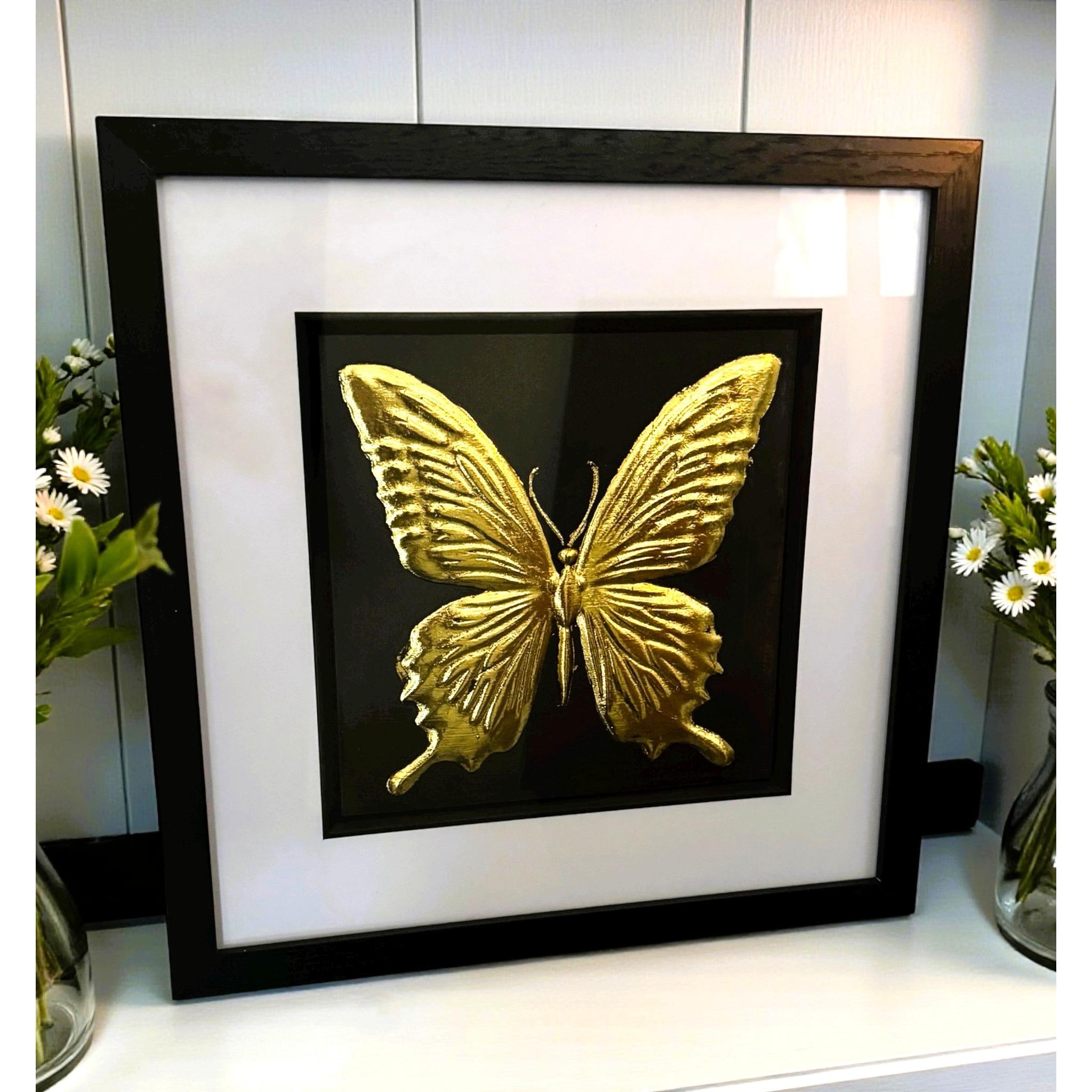 Gold butterfly framed wall art displayed on a shelf with floral styling
