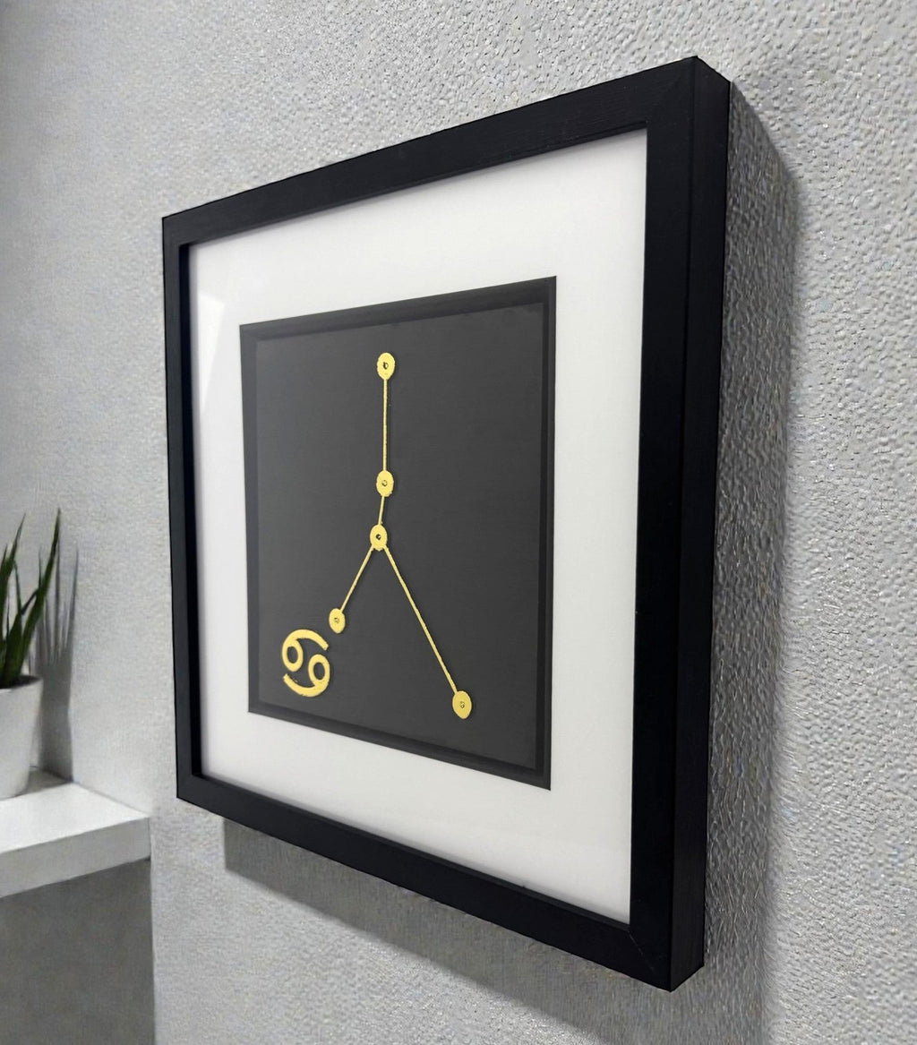 Framed Cancer constellation wall art in gold leaf mounted on a wall, shown at an angle highlighting the depth and clean presentation