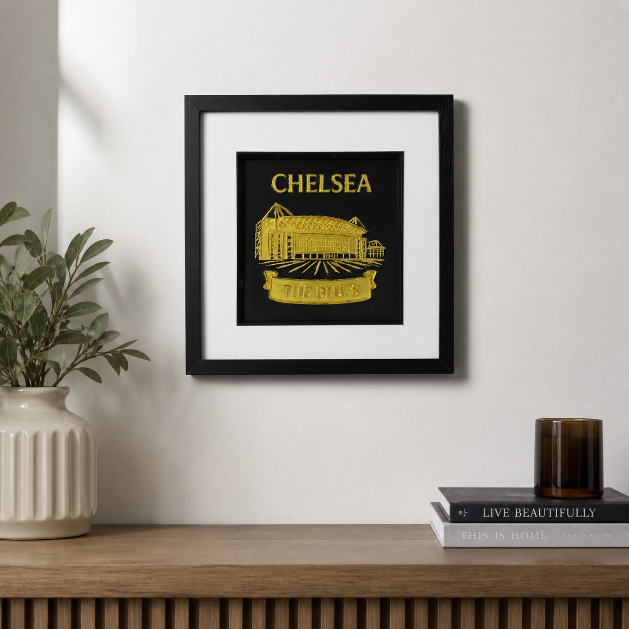 Lifestyle photo of Chelsea framed wall art displayed in a home interior on a wooden surface.