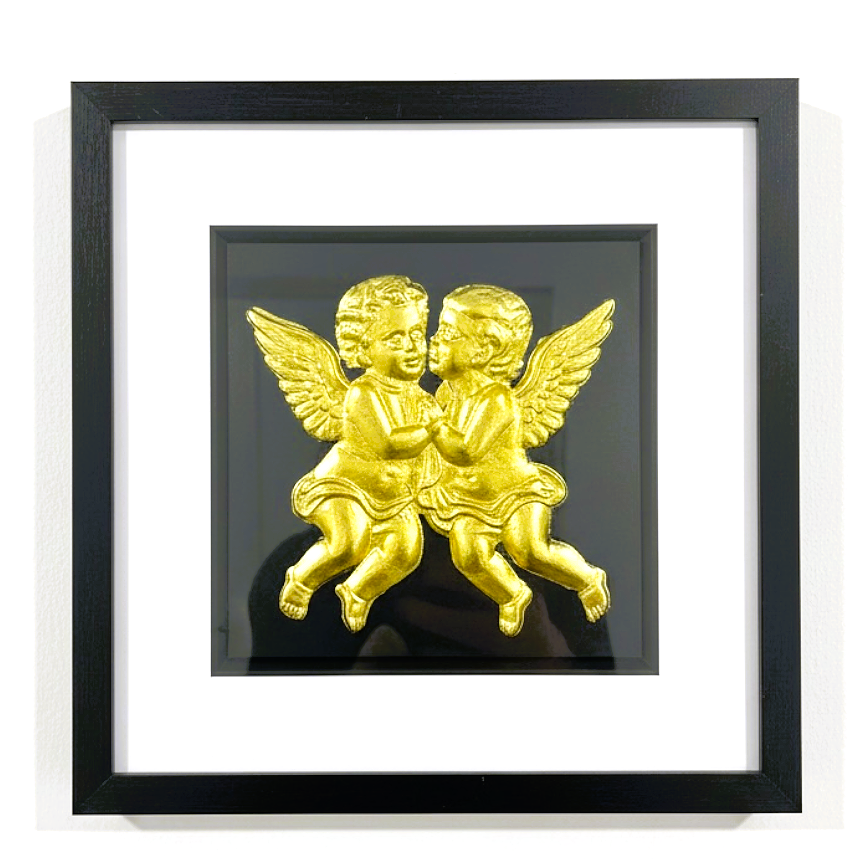 Front-facing gold leaf cherubs wall art on a black background within a black wooden frame
