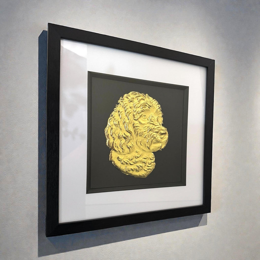 Gold cockapoo wall art displayed in a black frame with white mount, shown angled on a light wall to highlight depth and frame detail