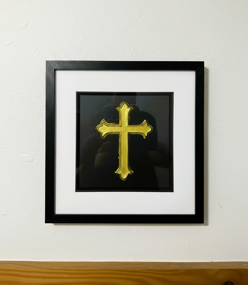 Gold leaf cross framed wall art mounted on a light-coloured wall, classic Christian design