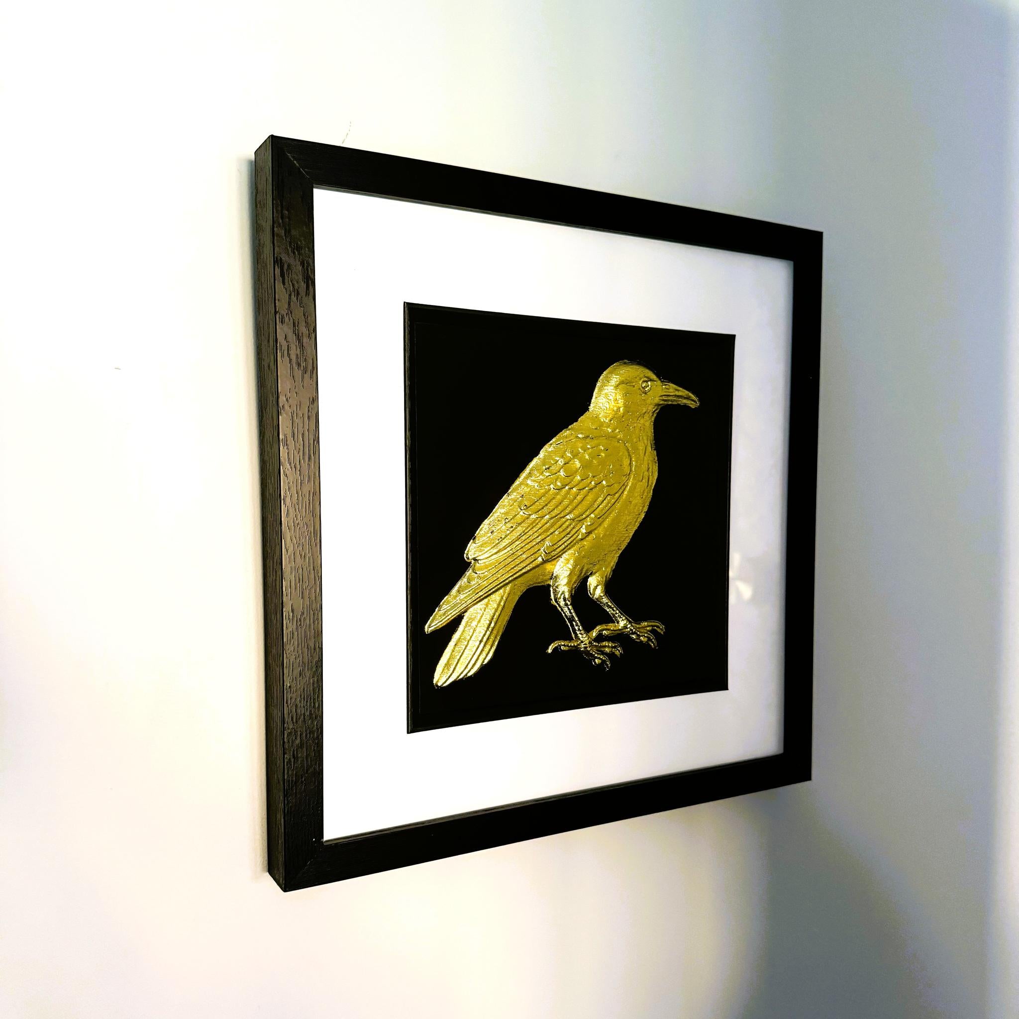 Angled view of gold leaf crow framed wall art with black frame and white mount