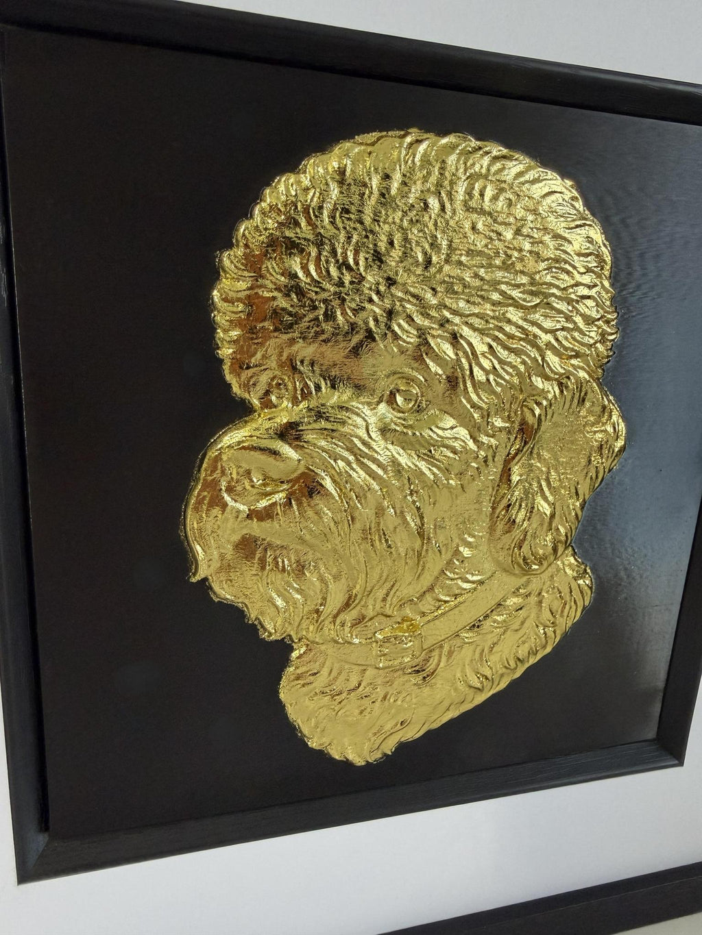 Close-up angled view of a gold Dandie Dinmont Terrier relief portrait showing the raised coat texture, beard detail, and collar.