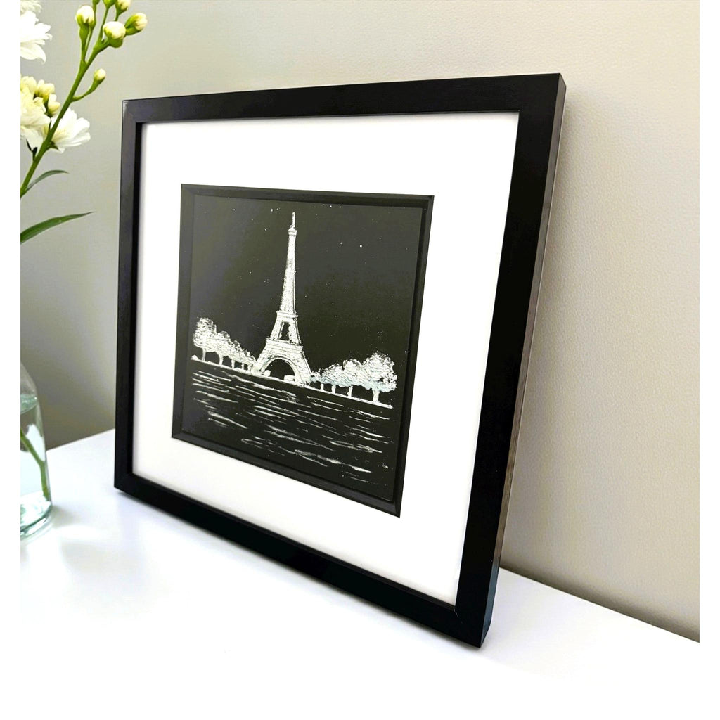 Eiffel Tower Paris wall art in black frame with white mount on a desk