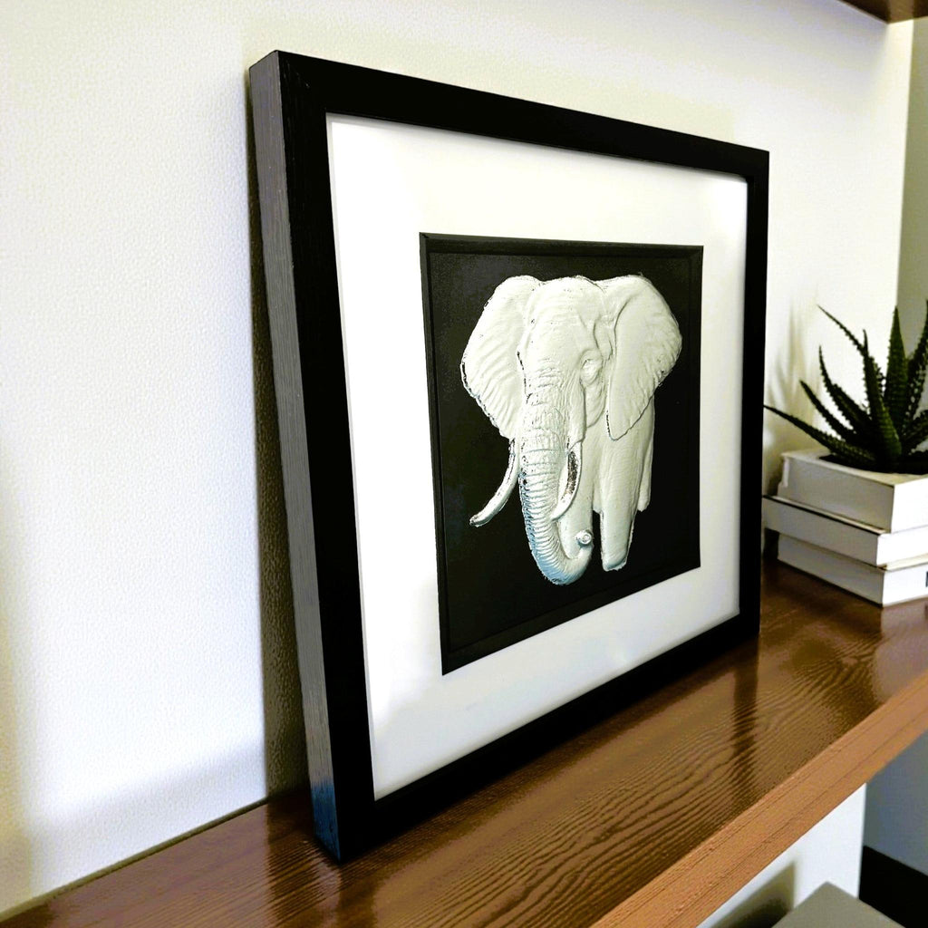 Silver elephant wall art displayed on a wooden shelf in a modern interior