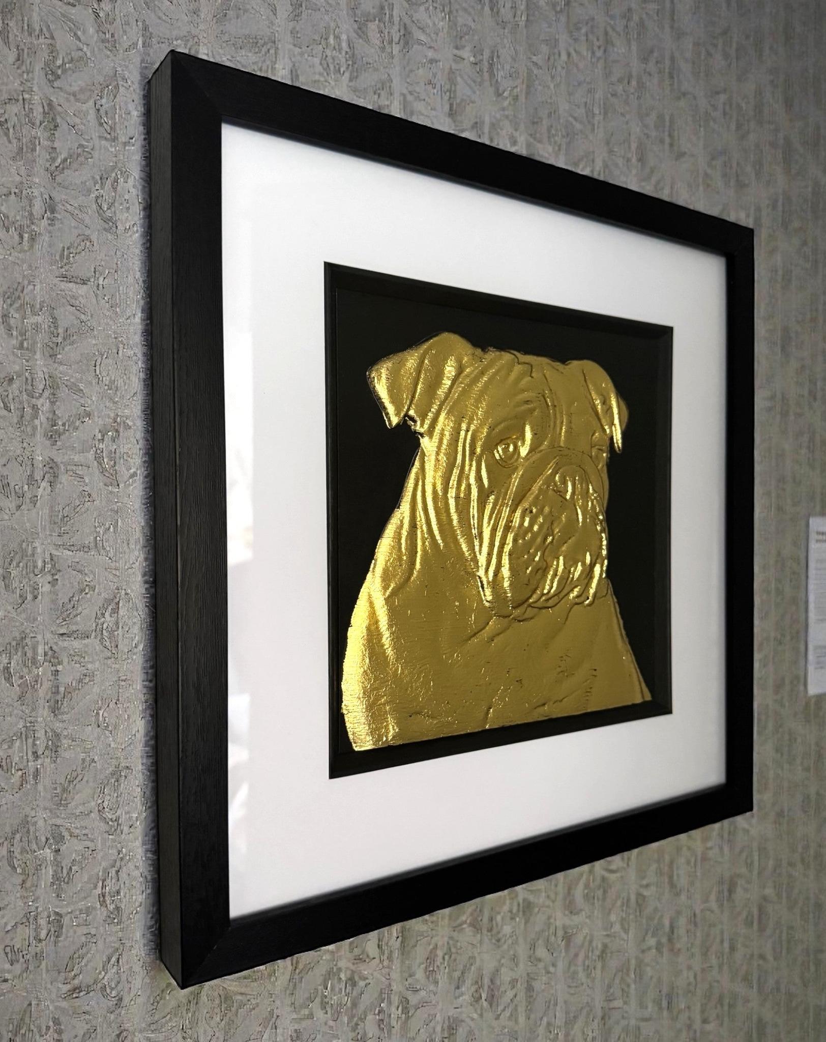 Framed English bulldog wall art in gold leaf relief mounted on a wall, shown at an angle highlighting the depth and texture of the artwork