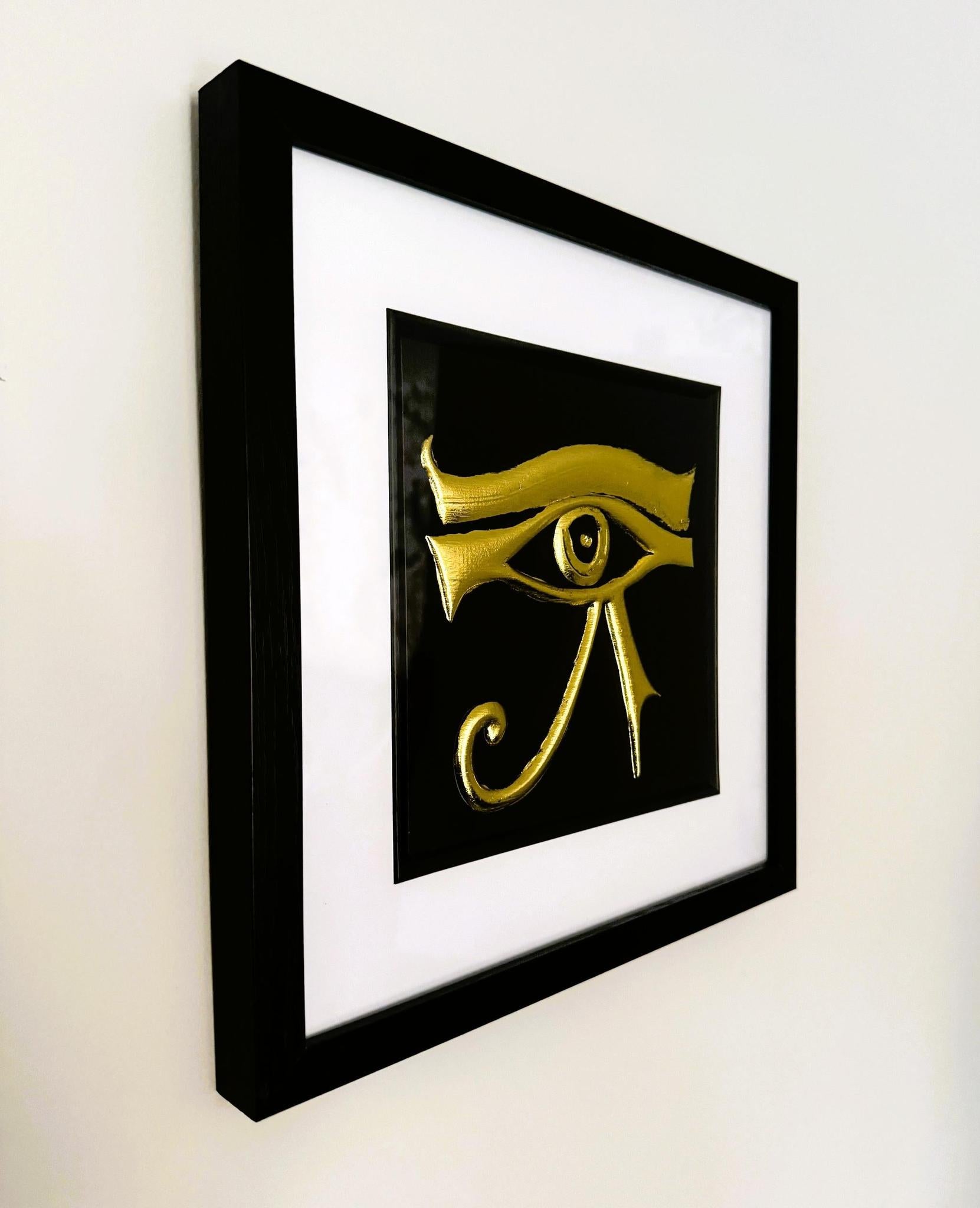 Angled wall-mounted gold leaf Eye of Horus framed wall art in a black wooden frame with white mount
