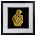 Gold father holding baby relief artwork in a black frame with white mount and black inner surround.