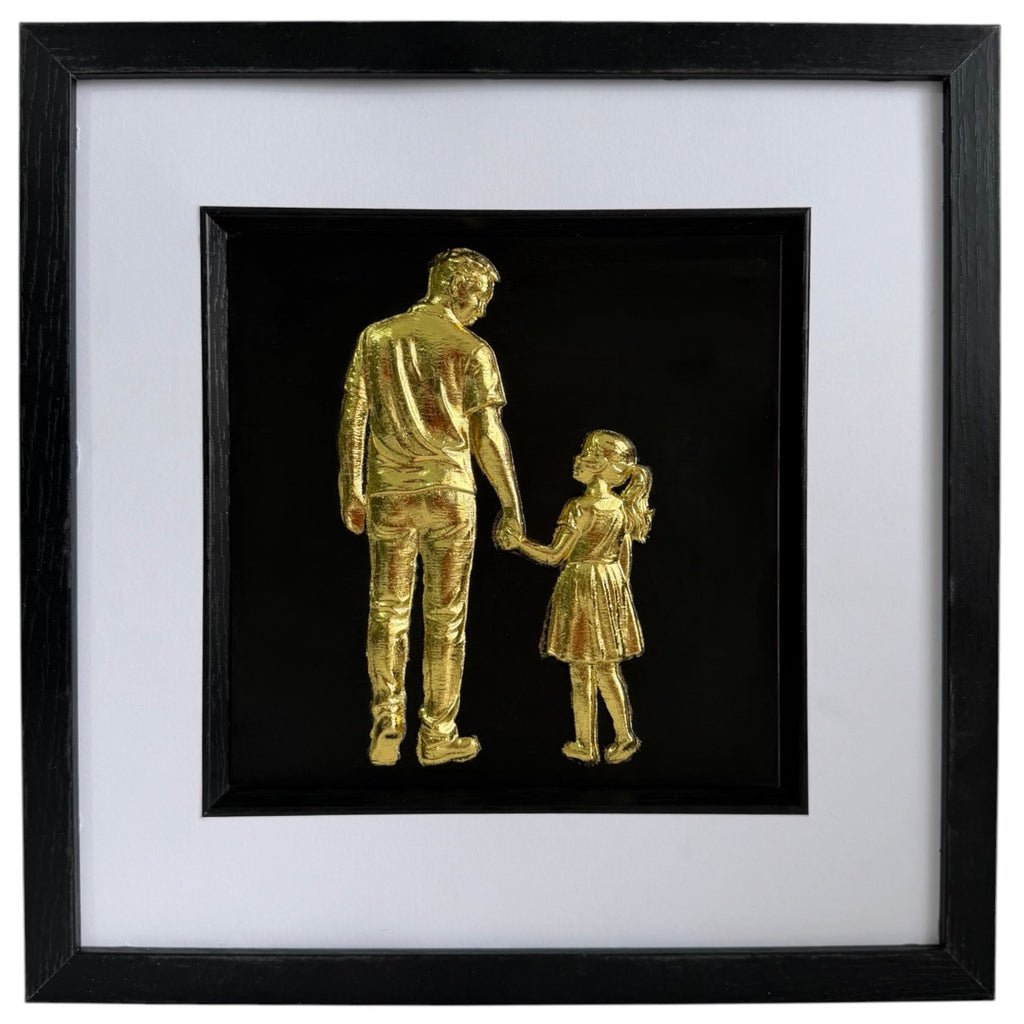 Framed gold leaf father and daughter wall art featuring a parent and child holding hands on a black background with a white mount and black frame.