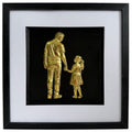 Framed gold leaf father and daughter wall art featuring a parent and child holding hands on a black background with a white mount and black frame.