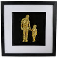 Gold father holding hands with son relief artwork in a black frame with white mount.