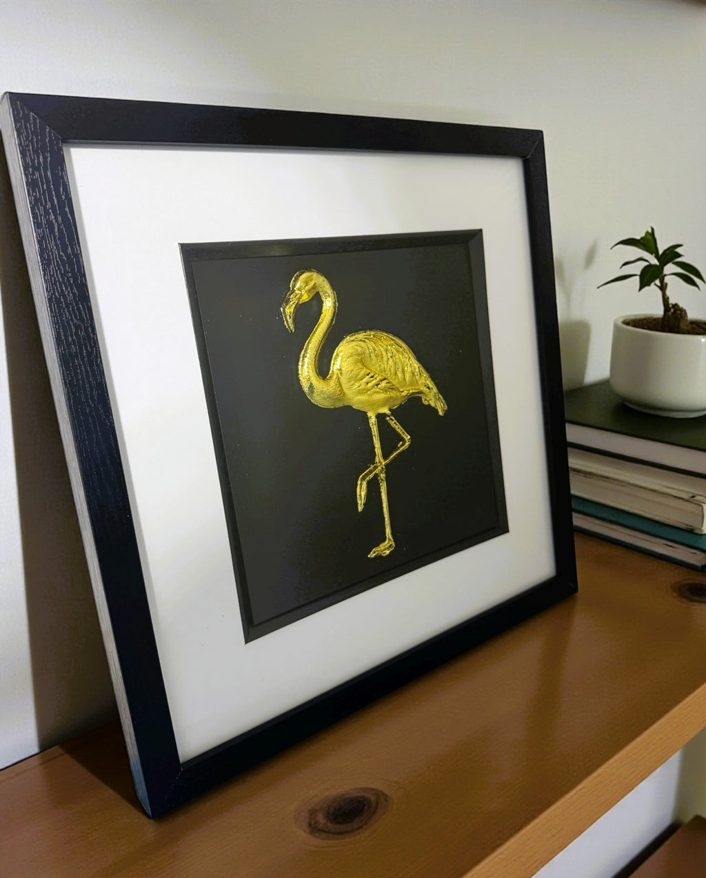 gold flamingo wall art side view on brown wooden sideboard
