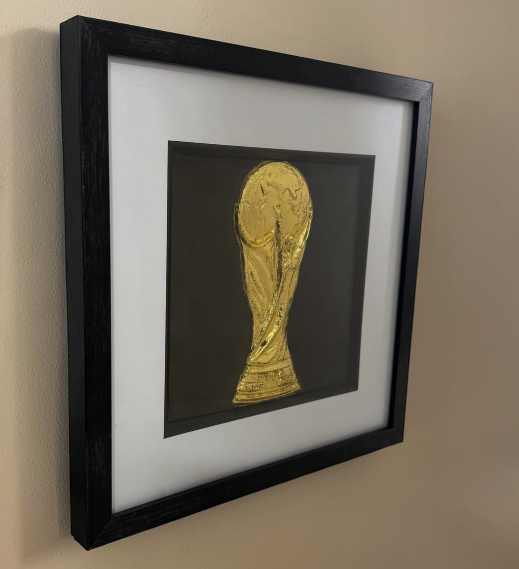Angled view of framed gold football trophy relief showing the deep black box frame and glass front.