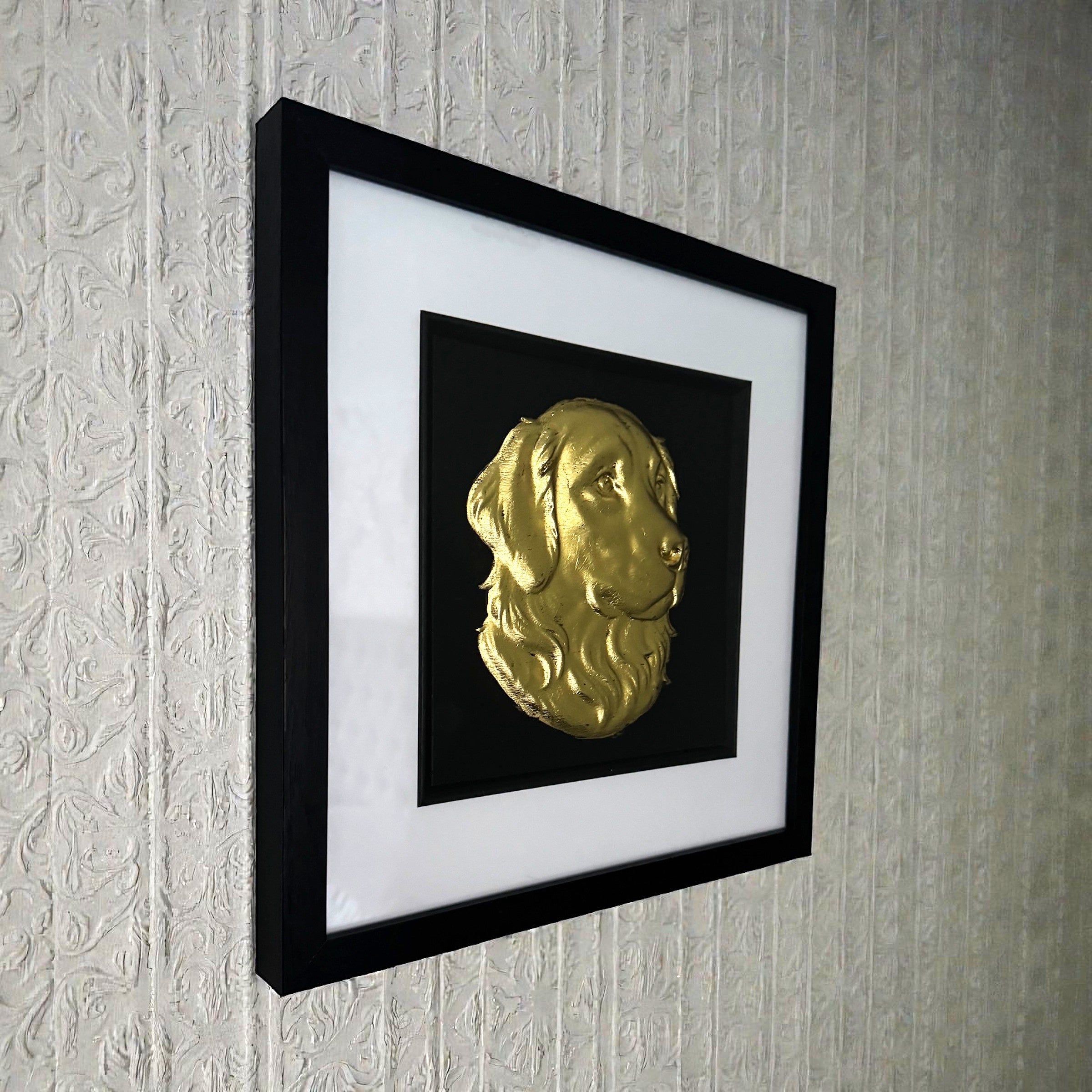 Golden Retriever framed wall art in gold leaf mounted on a wall, with black wooden frame, white mount, and black background
