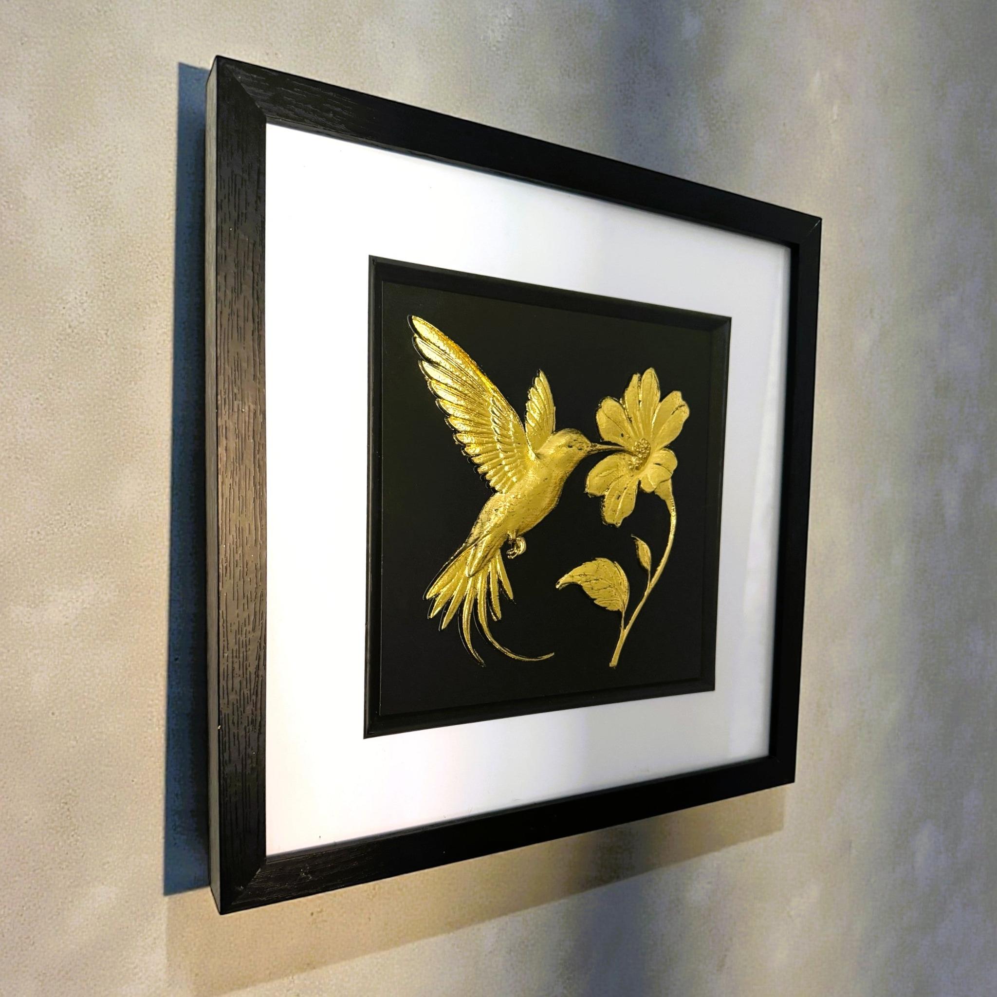 Angled wall-mounted view of gold leaf hummingbird and flower wall art showing frame depth