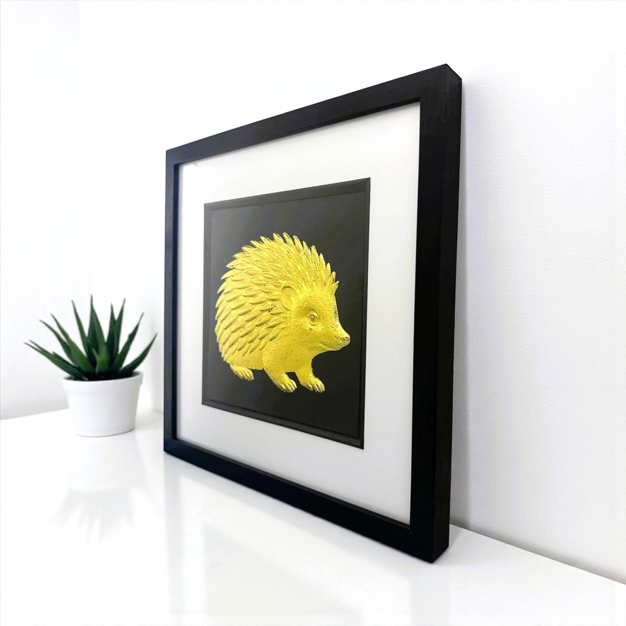 Angled view of gold leaf hedgehog framed wall art on a white shelf