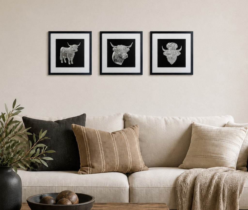 Silver trio styled above a neutral sofa with cushions, plant, wood coffee table and calm living room styling.
