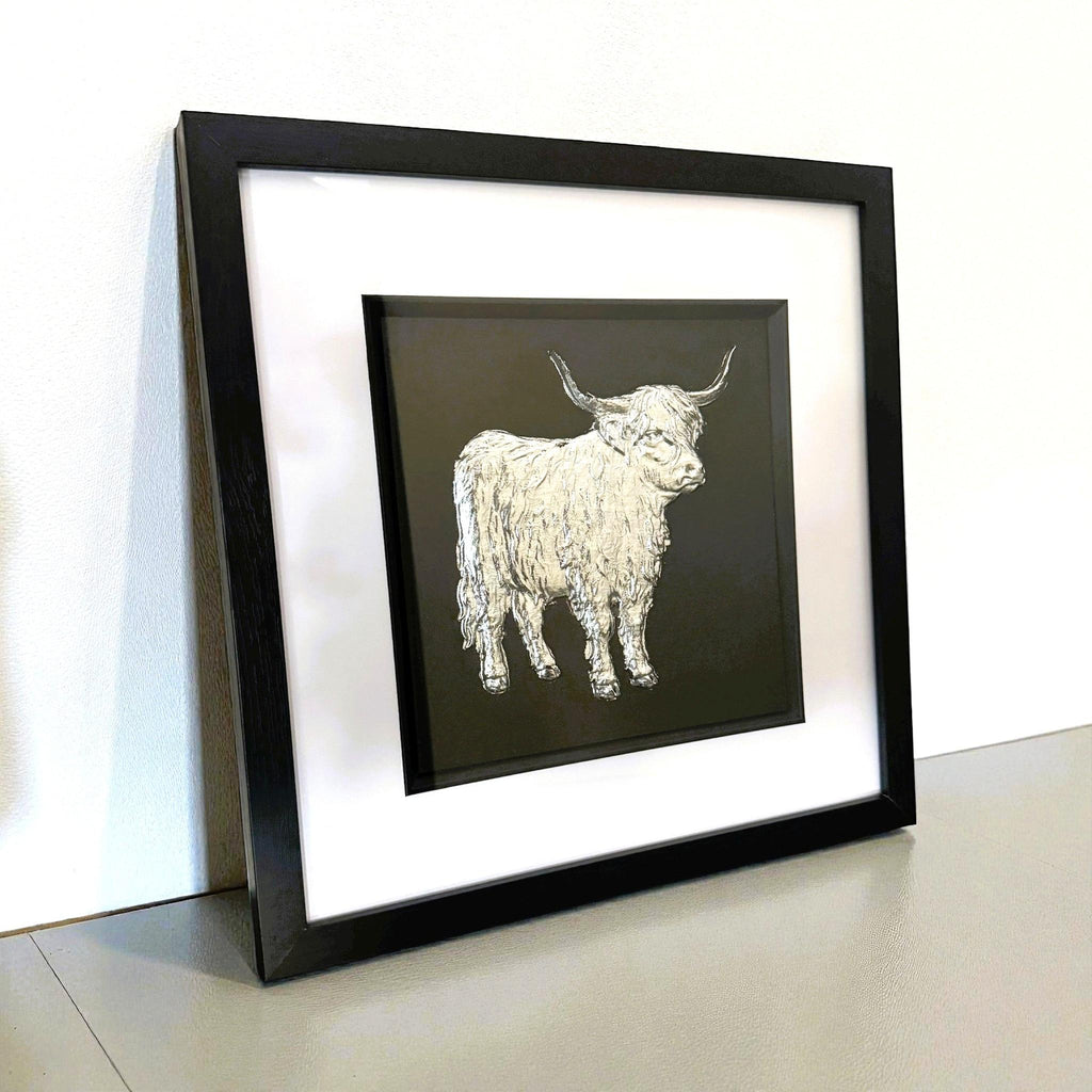 Silver Highland cow wall art displayed on a shelf with black frame
