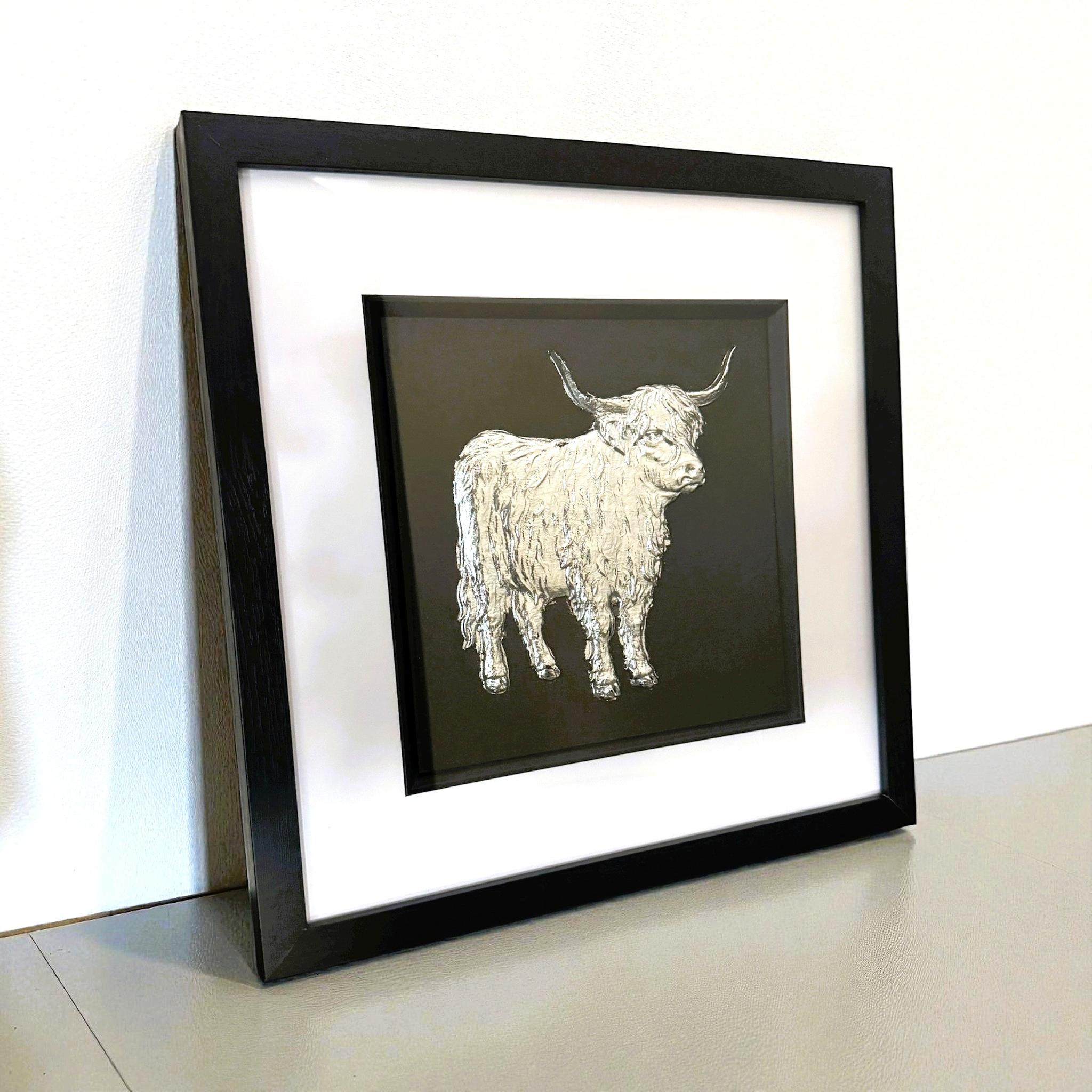 Silver Highland cow wall art displayed on a shelf with black frame