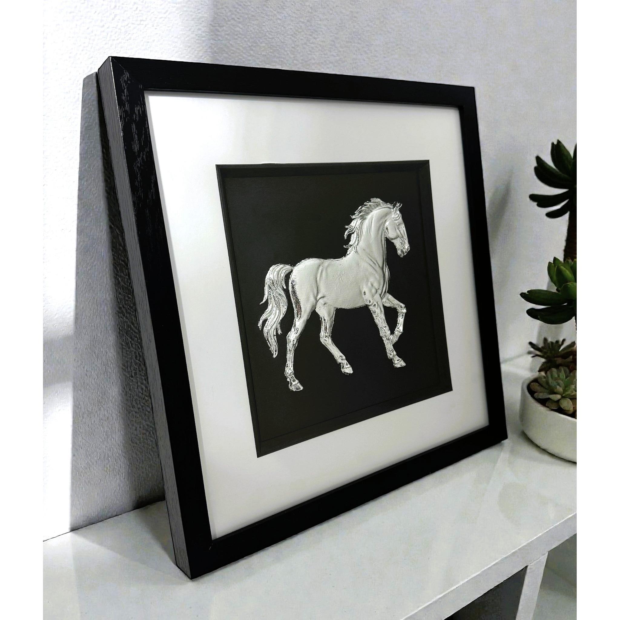 Silver horse wall art framed in black with white mount displayed on a shelf