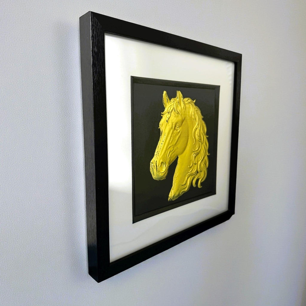 Gold horse head wall art framed in black hanging on a wall
