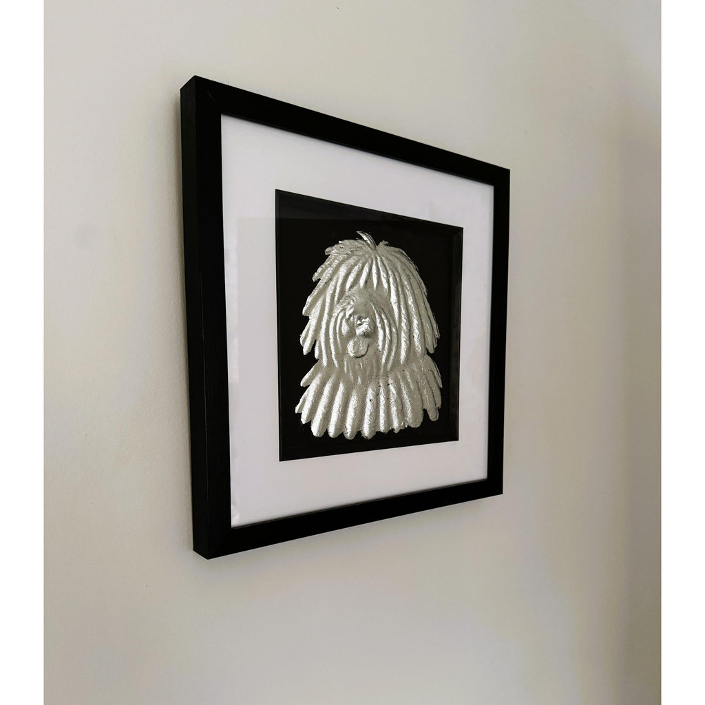 Hungarian Puli framed wall art in silver leaf mounted on a wall, with black wooden frame, white mount, and black background
