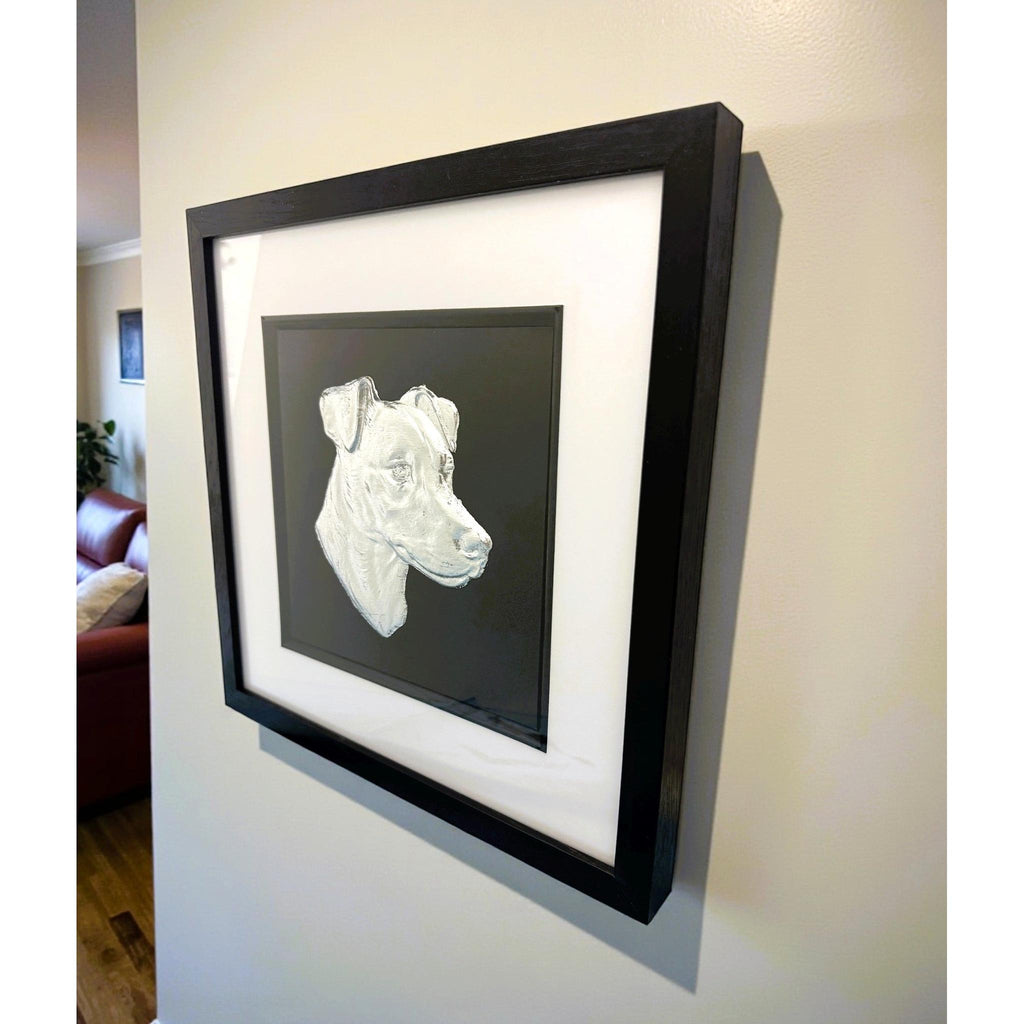 Jack Russell Terrier framed wall art in silver leaf mounted on a wall, with black wooden frame, white mount, and black background
